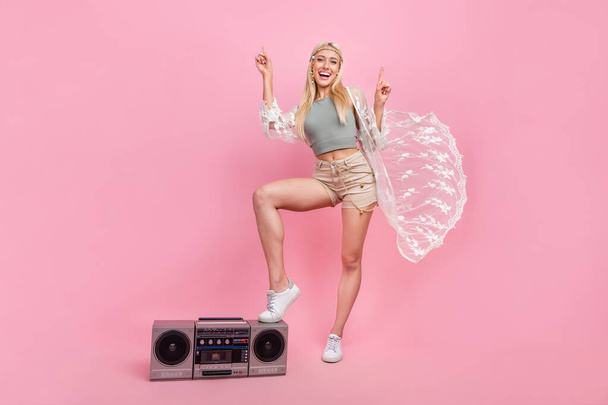 Full length photo of young blond lady index up with boombox wear top cape shorts shoes isolated on pink background - Photo, Image