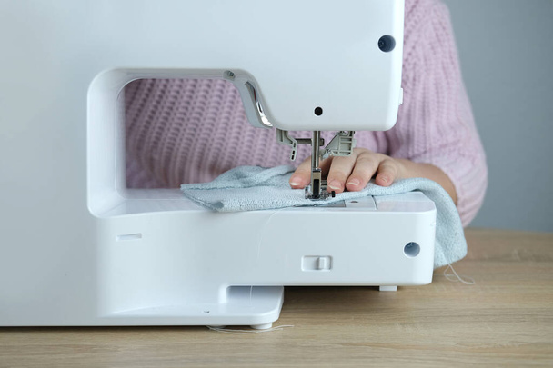 close-up of female hands perform work on a white sewing electric computer machine, stitches appear step by step on the fabric, concept of tailoring, women's hobby, modern needlework - Foto, immagini