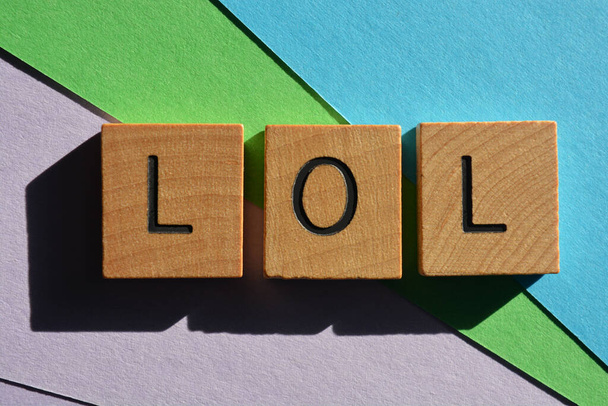 LOL acrónimo de Laughing Out Loud, en letras de alfabeto de madera aisladas sobre un fondo colorido - Foto, imagen