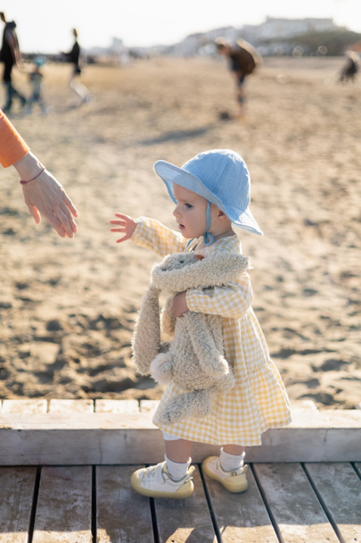 Baby girl holding toy near mom on pier in Treviso - Foto, afbeelding