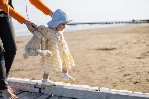 Woman holding toy near toddler daughter on pier in Treviso - Photo, Image