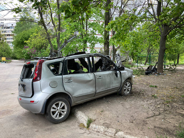A damaged car in Kharkov as a result of shelling of a peaceful city by Russian troops. Bombing of residential buildings by Russian assassins. - Foto, Imagen