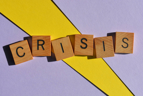 Crisi, parola in alfabeto di legno lettere isolate su sfondo viola e giallo - Foto, immagini