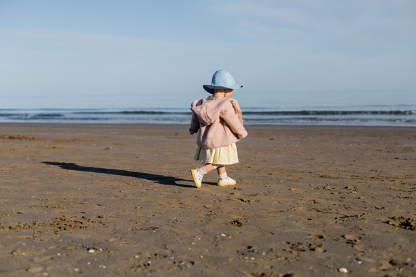 Bébé fille en chapeau panama marchant sur la plage en Italie  - Photo, image
