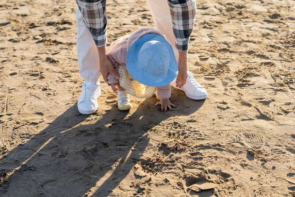 Homme soutenant bébé fille sur la plage de sable fin  - Photo, image