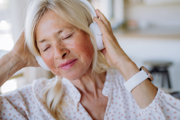 Senior woman with headphones listening to relaxation music at home - Fotografie, Obrázek