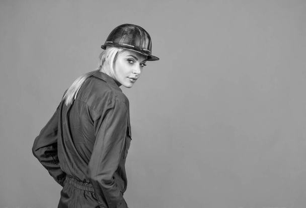 woman worker in protective helmet and boilersuit on orange background, copy space, 1 may - Photo, Image