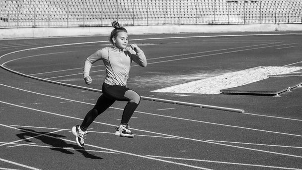 teen girl running on outdoor stadium racing track, marathon - Fotó, kép