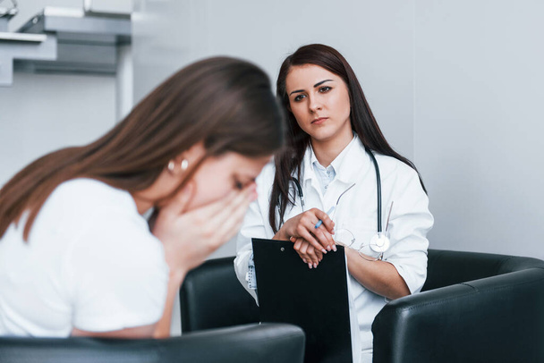 Girl have mental breakdown and crying. Young woman have a visit with female doctor in modern clinic. - Φωτογραφία, εικόνα