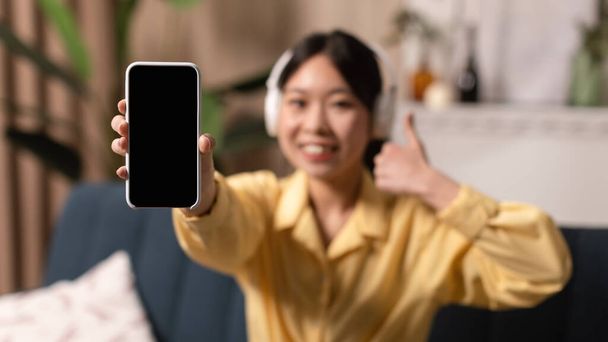 Smiling Asian woman showing blank phone screen and like, mockup - Foto, Imagem