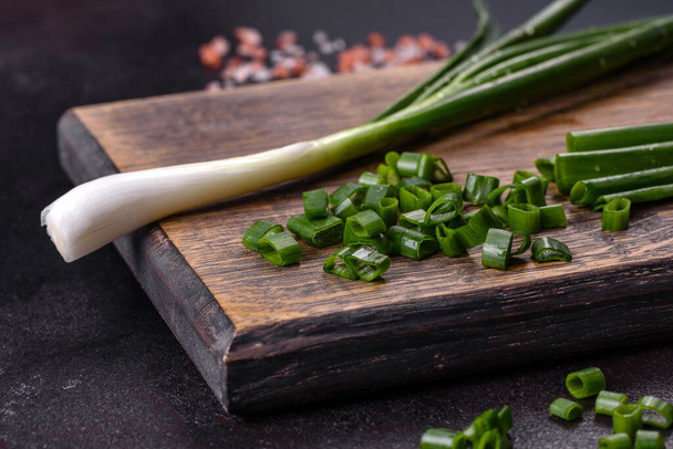 Cut Green onions chives on a cutting board. Dark concrete background - Foto, Imagem