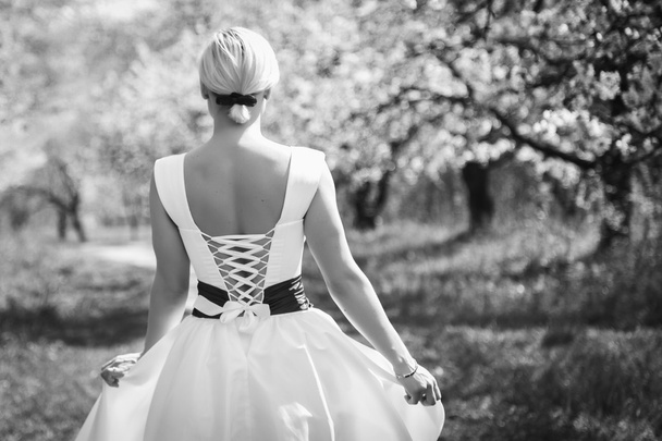 Ξανθιά σε λευκό φόρεμα στον κήπο άνοιξη - Φωτογραφία, εικόνα