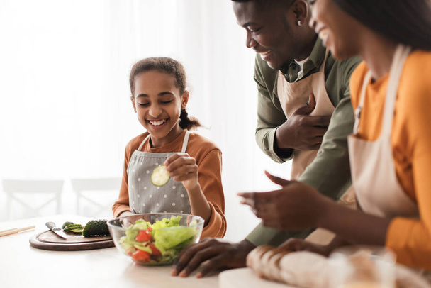 Χαρούμενη μαύρη οικογένεια κάνοντας σαλάτα μαγείρεμα στην κουζίνα, επιλεκτική εστίαση - Φωτογραφία, εικόνα