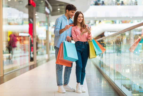 Szczęśliwi małżonkowie Zakupy przy użyciu smartfona i karty kredytowej w centrum handlowym - Zdjęcie, obraz