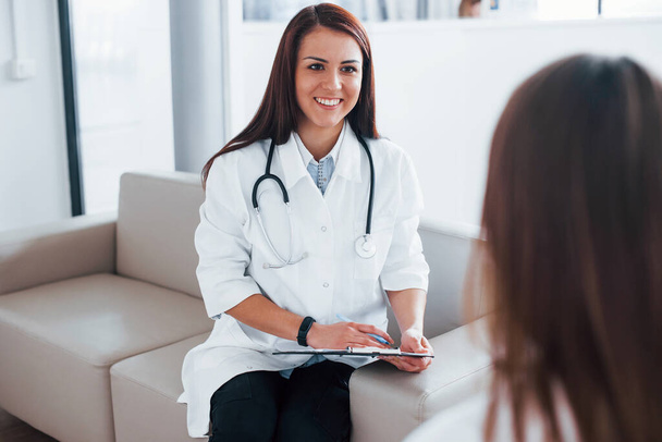 Friendly doctor listening to the patient. Young woman have a visit with female doctor in modern clinic. - Foto, Imagen