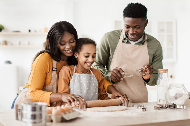 alegre familia negra hornear pastelería rodar fuera masa en cocina - Foto, Imagen