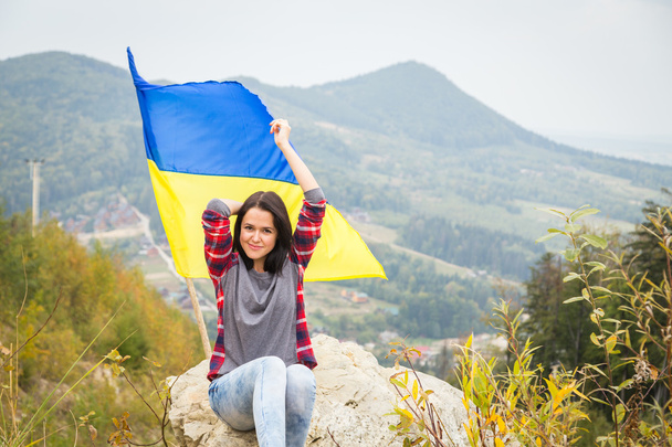 woman on mountain top with Ukrainian flag - Foto, imagen