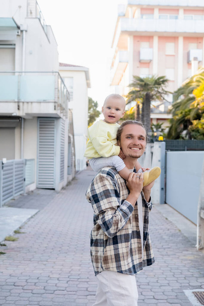 Homme tenant bébé fille souriante dans la rue urbaine de Trévise - Photo, image