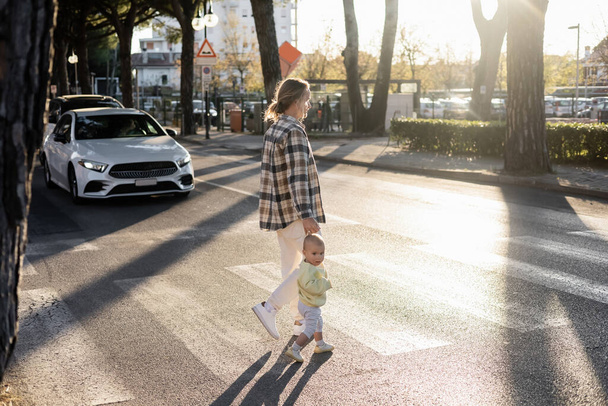 父と幼児の女の子はトレヴィーゾの都市の通りを横断歩道を歩く - 写真・画像