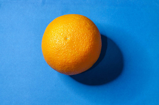 Big orange orange on a blue background - Φωτογραφία, εικόνα