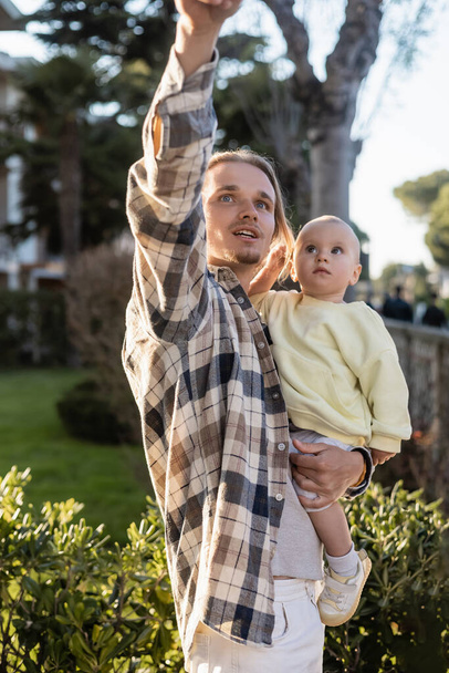 Mężczyzna odwraca wzrok trzymając córeczkę na zewnątrz w Treviso - Zdjęcie, obraz