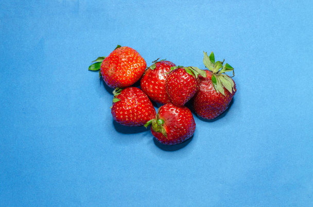 Red fresh strawberries on a blue background - Fotó, kép