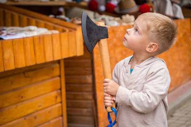 Маленький хлопчик тримає дерев'яну сокиру
 - Фото, зображення