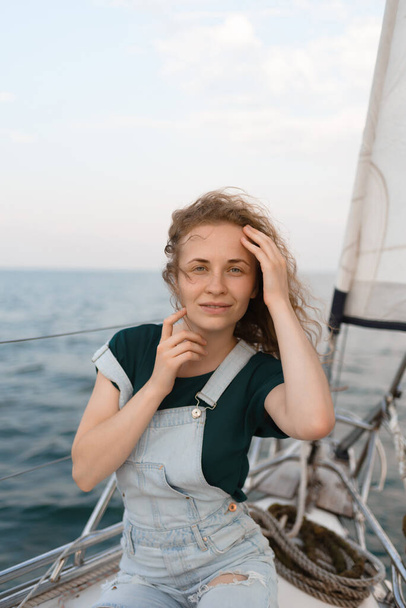 Genç bir kadın okyanusta yelkenli yolculuğunun tadını çıkarıyor. Yatla lüks bir yolculuk. - Fotoğraf, Görsel