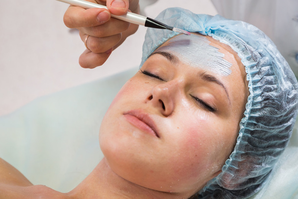 Therapeut trägt Gesichtsmaske auf Frau auf - Foto, Bild