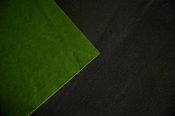 Krásný zelený ubrousek leží na černém texturovém stole s rohem na straně. Mezera pro štítky - Fotografie, Obrázek