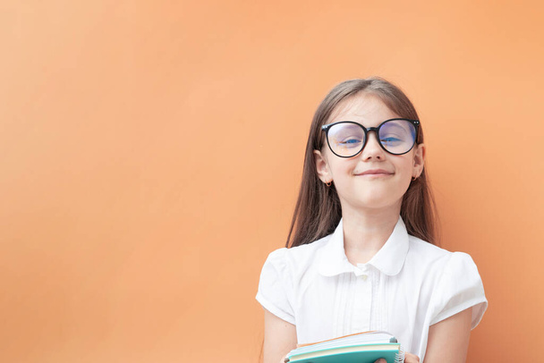 Ein 7-jähriges Mädchen mit Brille, Notizbüchern und zufriedenem Gesicht. Bildung, Lernkonzept für Kinder. - Foto, Bild