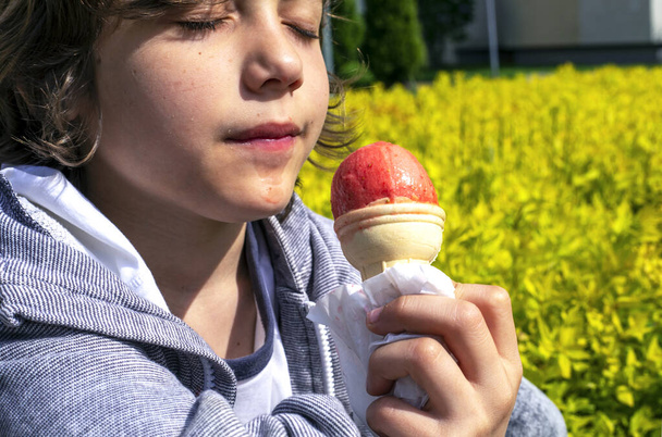 щасливий хлопчик із закритими очима насолоджується смаком полуничного натурального морозива на прогулянці сонячним днем з місцем для тексту
 - Фото, зображення