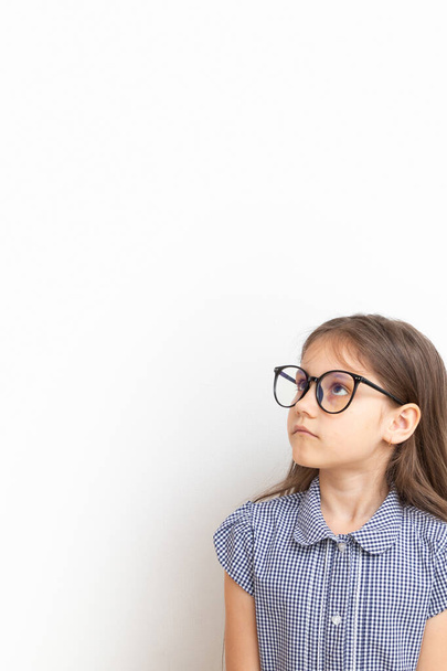 A 7-year-old girl with glasses with sad faces. Children's education, learning concept with copy space. Vertical format. - Fotografie, Obrázek