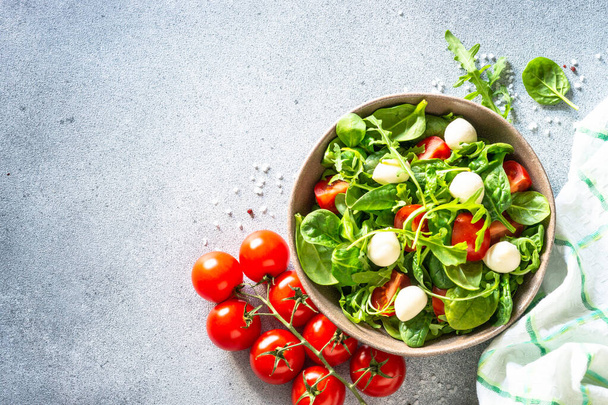 Green salad with fresh leaves, tomatoes and mozzarella. Top view, copy space. - Fotoğraf, Görsel