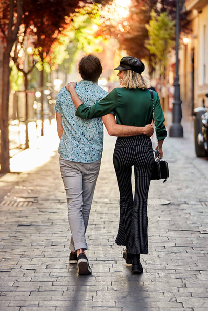 Couple walking on street away from camera. - Photo, image