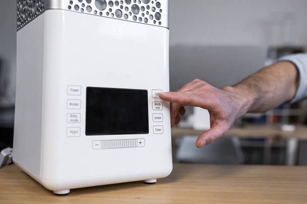 Close up photo. A man's hand that includes a desktop humidifier or air conditioner on the desktop near the computer - 写真・画像