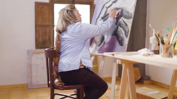 Καλλιτέχνης ώριμη γυναίκα ξοδεύει τον ελεύθερο χρόνο της αναπτύσσοντας τις δεξιότητες ζωγραφικής στο εργαστήριό της - Πλάνα, βίντεο