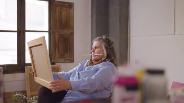 Olgun sanatçı kadın, atölyesinde boş zamanlarında geliştirdiği eserlerinden birini görüyor. - Video, Çekim