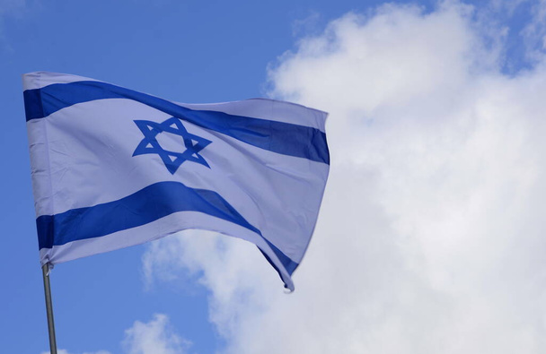 Flag of Israel. Israel flag close up shot on a background of blue sky. White and blue colors. Israel flag waving against clean blue sky - Fotó, kép
