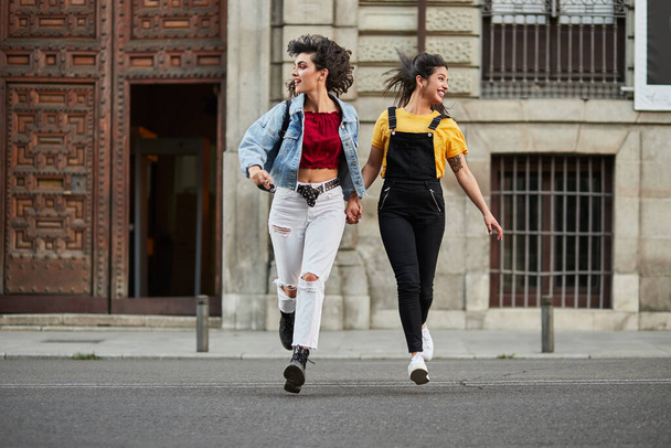Two teenager girls running down street. - Fotoğraf, Görsel