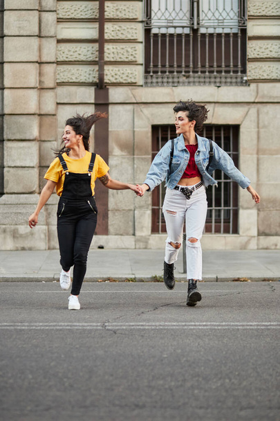 Two teenager girls running down street. - Valokuva, kuva