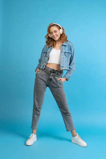 Portrait of young pretty happy girl in casual style outfit isolated on blue background. Concept of beauty, art, fashion, youth, spring collection - Zdjęcie, obraz