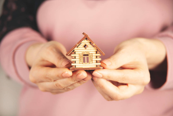 mão mulher segurando modelo de casa de madeira no fundo cinza - Foto, Imagem