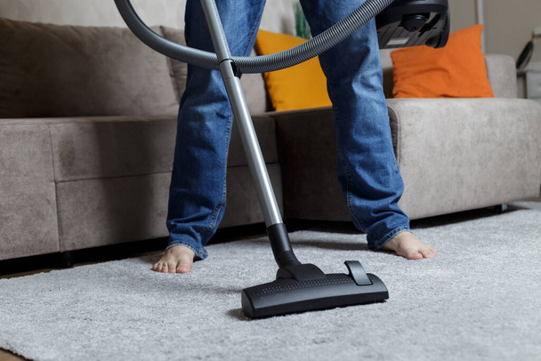 a man in jeans is vacuuming. House cleaning - Photo, image