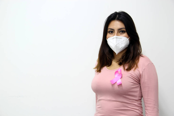 Latin woman with pink blouse and pink ribbon for campaign against breast cancer on white background - Foto, imagen