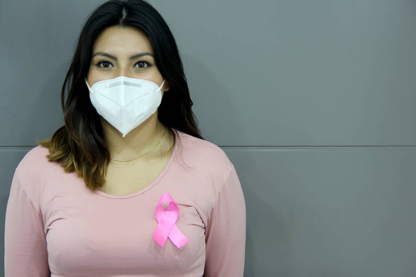 Latin woman with pink blouse and pink ribbon for campaign against breast cancer on white background - Foto, imagen