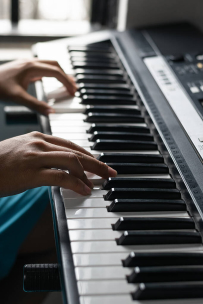 detailed view of the hands of a young latin man composing melodies on his electronic piano or synthesizer. boy practicing his virtual lessons from home. brown man practicing his hobby. - Foto, Imagem