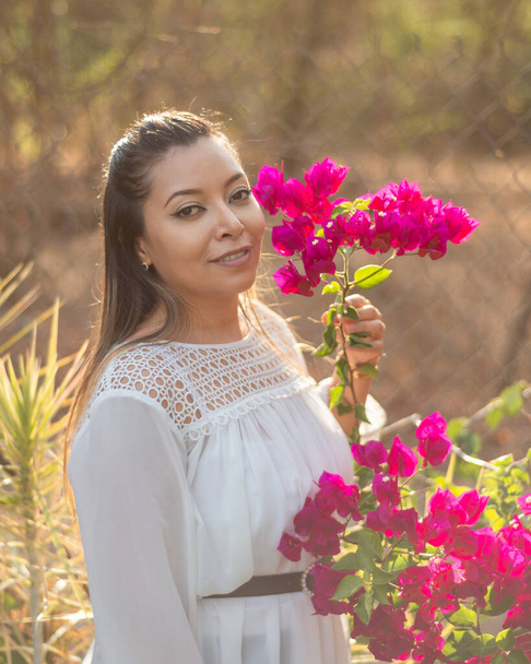 Portrait of a woman in a garden. Portrait of Mexican woman next to a flowering bougainvillea plant. - Photo, Image