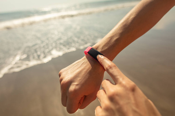 Ocean waves on beach with wearable technology on wrist monitoring sports and exercise activity for health and fitness - Foto, Imagen
