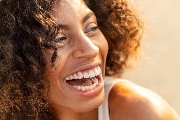 Laughing young African American girl having fun on solo vacation enjoying leisure time in Summer sun on beach - Photo, Image